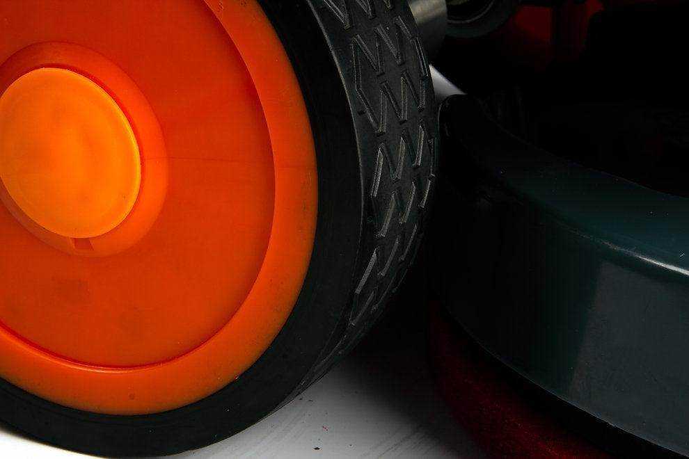 Close-up of the orange wheel and scrubbing brush of a SUNMAX RT50D Self-Propelled Floor Scrubber.